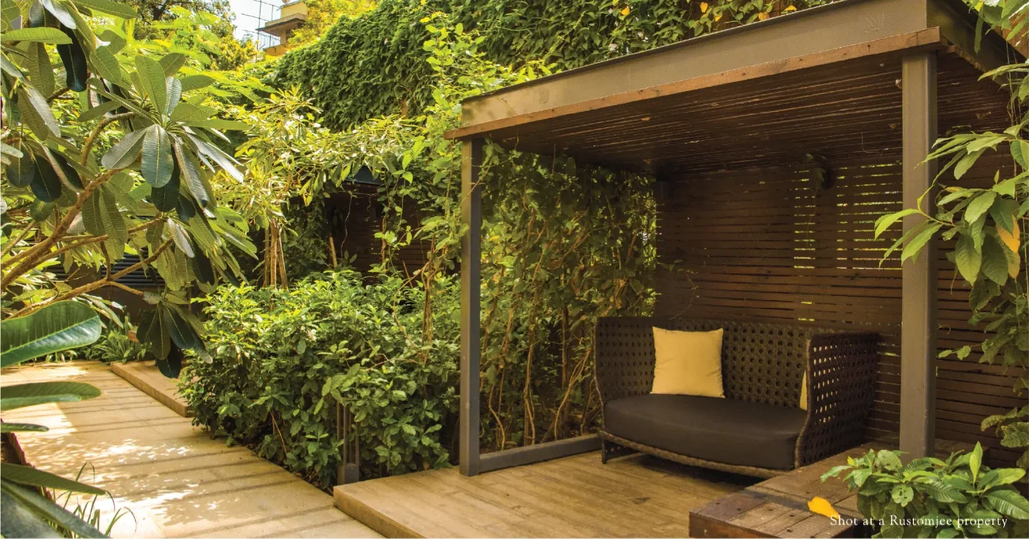 Shaded timber deck and garden seating in a landscaped courtyard at a Rustomjee property