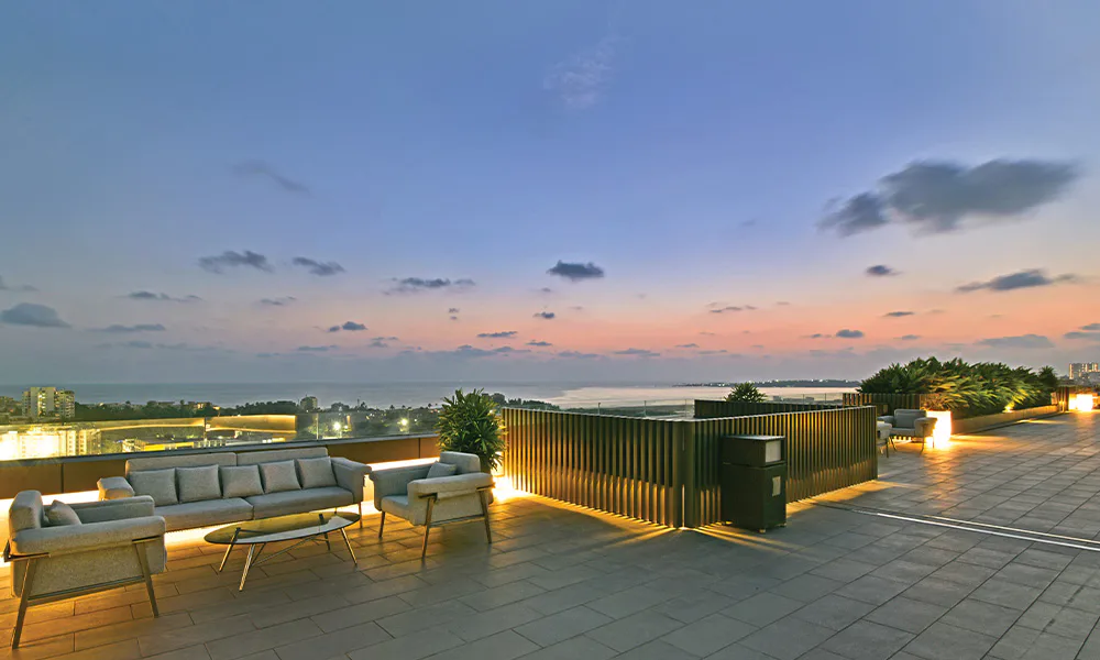 Rooftop deck with lounge seating at dusk at Rustomjee Urban Woods