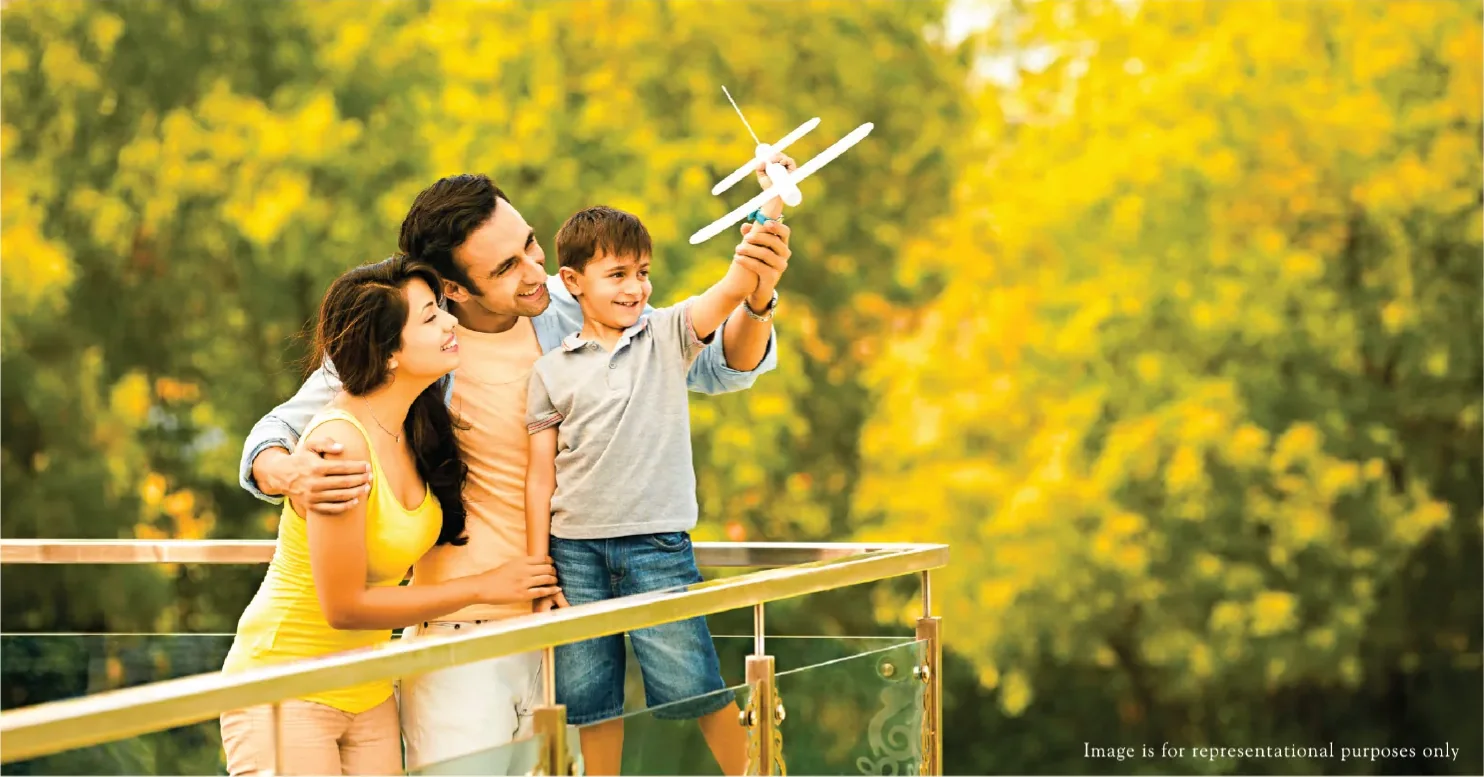 Family on a wide sundeck with a glass balustrade, from the Rustomjee Urban Woods brochure